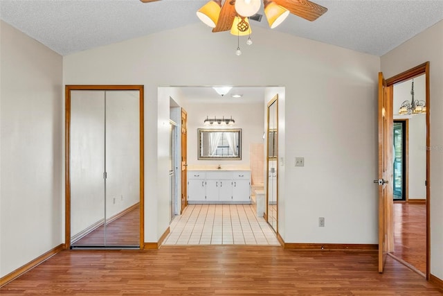 interior space with light wood-type flooring, a textured ceiling, and vaulted ceiling