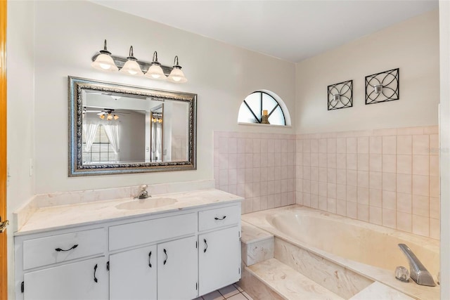 bathroom with tile patterned floors, vanity, ceiling fan, and tiled bath