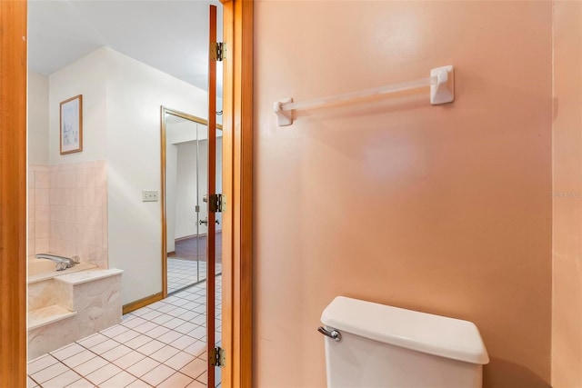 bathroom with tile patterned floors, a tub, and toilet