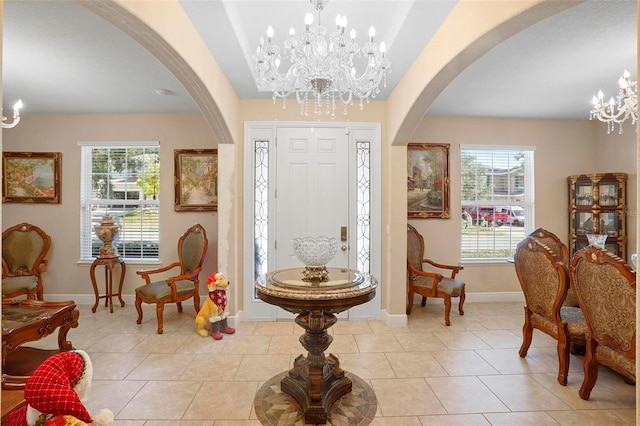 foyer entrance with a notable chandelier, plenty of natural light, and light tile patterned flooring