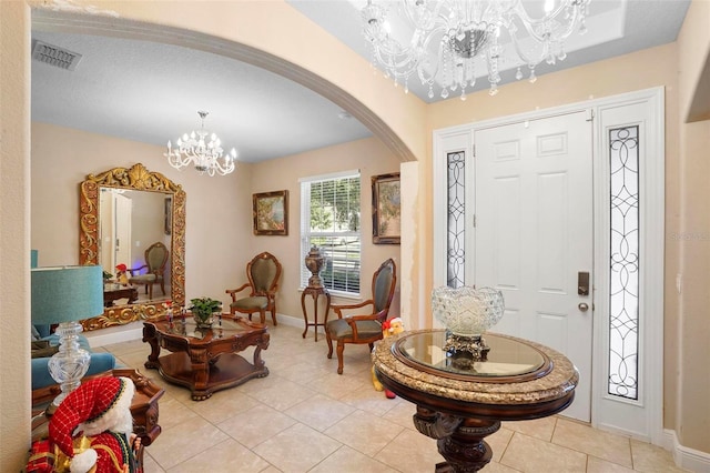 tiled foyer with a textured ceiling and an inviting chandelier