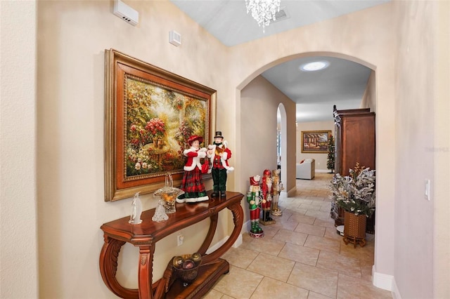 hallway with a notable chandelier and light tile patterned flooring