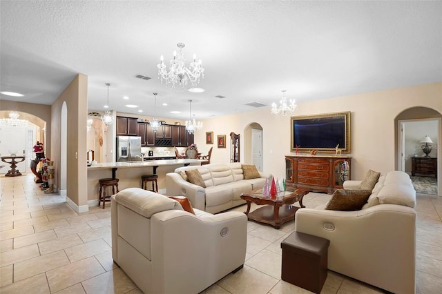 tiled living room featuring a chandelier and a textured ceiling