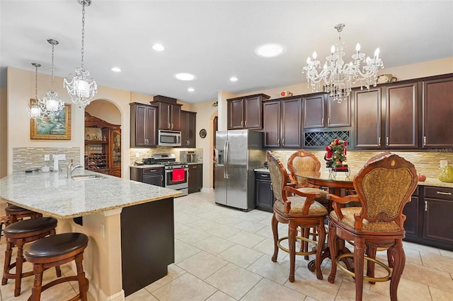 kitchen with pendant lighting, backsplash, a kitchen bar, kitchen peninsula, and stainless steel appliances