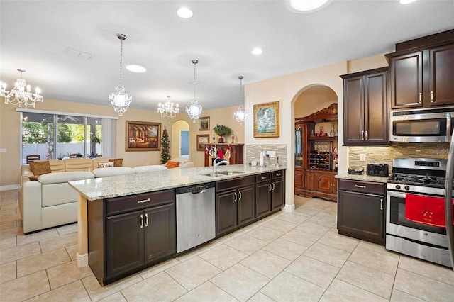 kitchen with a chandelier, pendant lighting, stainless steel appliances, and dark brown cabinets