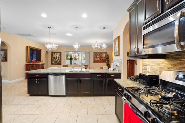 kitchen with pendant lighting, light stone counters, sink, and stainless steel appliances