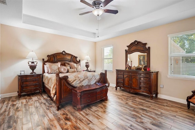 bedroom featuring multiple windows, hardwood / wood-style floors, and ceiling fan