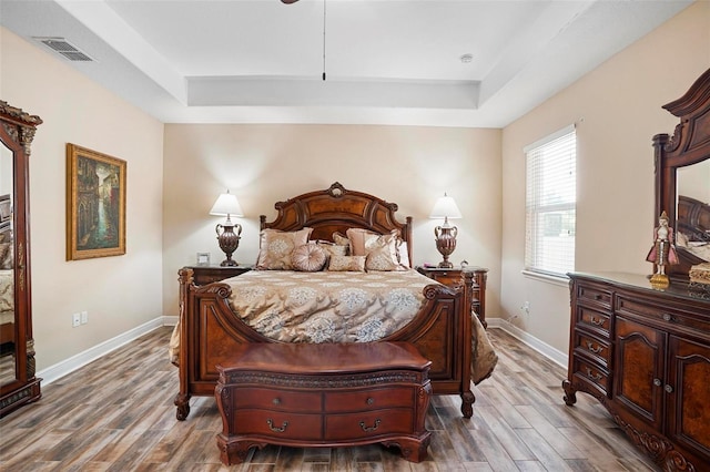 bedroom with hardwood / wood-style floors and a tray ceiling