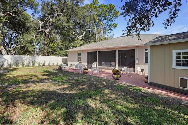 rear view of property with a sunroom, a patio area, and a yard