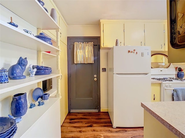 kitchen with cream cabinetry, white appliances, and dark wood-type flooring