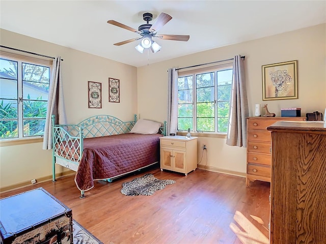 bedroom featuring ceiling fan, light wood-type flooring, and multiple windows