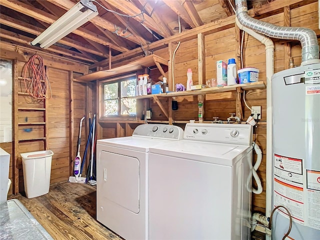 clothes washing area featuring washing machine and clothes dryer, wood-type flooring, wood walls, and water heater