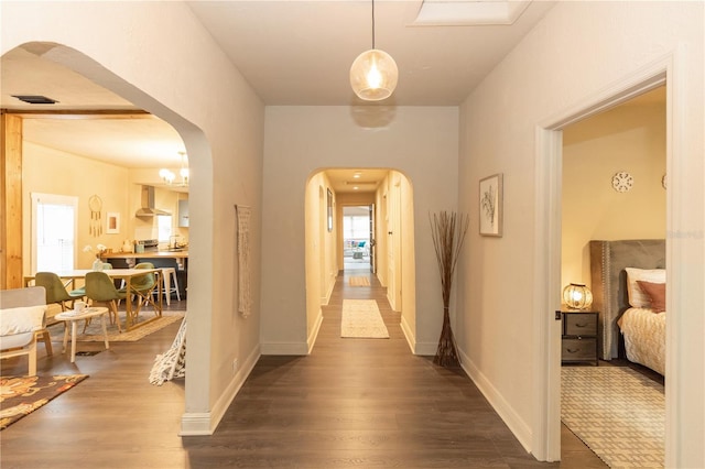 corridor with hardwood / wood-style flooring and an inviting chandelier