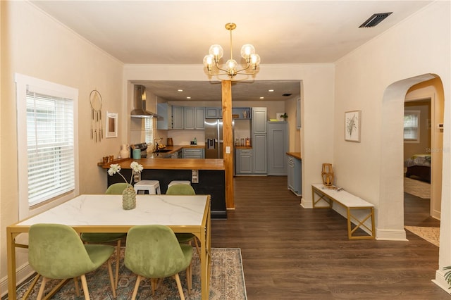 dining space featuring dark hardwood / wood-style floors, ornamental molding, sink, and a chandelier