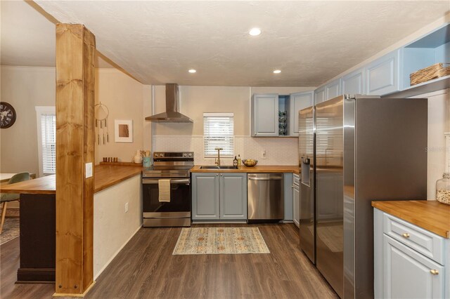 kitchen featuring stainless steel appliances, sink, wall chimney range hood, butcher block countertops, and dark hardwood / wood-style floors