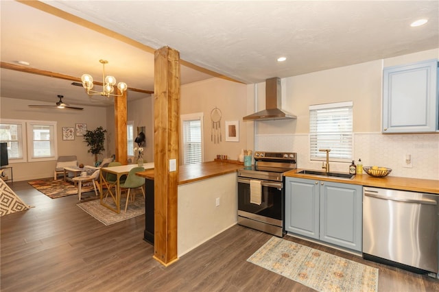 kitchen featuring butcher block countertops, a healthy amount of sunlight, wall chimney range hood, and appliances with stainless steel finishes