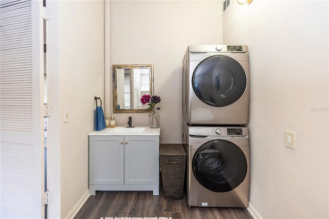 washroom featuring cabinets, dark hardwood / wood-style flooring, stacked washer / drying machine, and sink