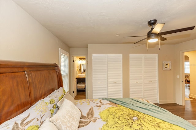 bedroom with ceiling fan, dark hardwood / wood-style floors, and two closets