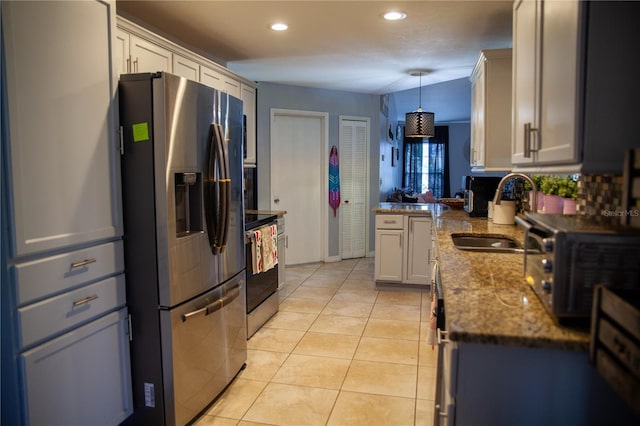 kitchen featuring appliances with stainless steel finishes, white cabinetry, sink, hanging light fixtures, and light tile patterned floors