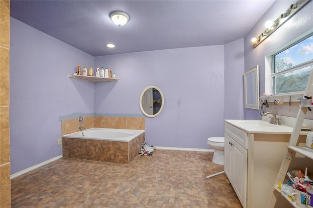 bathroom featuring tiled bath, vanity, a textured ceiling, and toilet