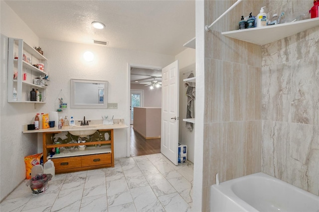 bathroom featuring sink, hardwood / wood-style flooring, ceiling fan, a textured ceiling, and tub / shower combination