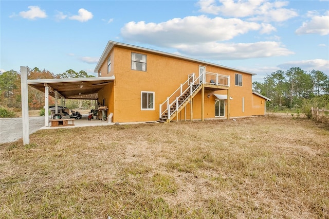 back of house featuring a carport and a lawn