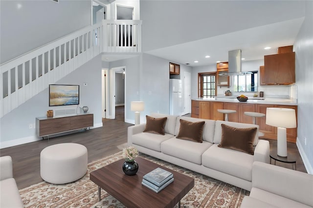 living room with a towering ceiling and dark hardwood / wood-style floors