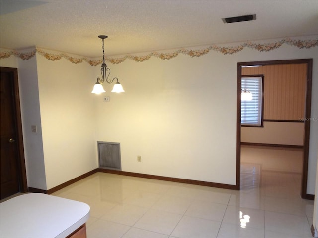 spare room featuring an inviting chandelier, light tile patterned floors, visible vents, and a textured ceiling