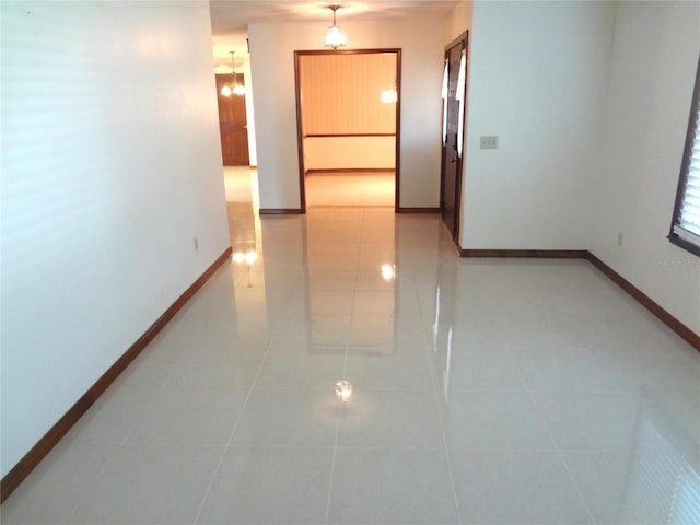 corridor featuring an inviting chandelier, light tile patterned floors, and baseboards