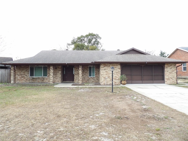 single story home featuring driveway, brick siding, an attached garage, and a front lawn