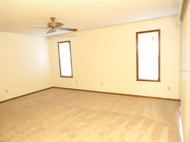 unfurnished room featuring baseboards, light carpet, a textured ceiling, and ceiling fan