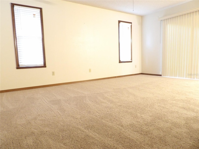 spare room with baseboards and light colored carpet