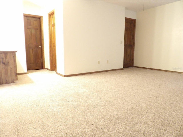 spare room with light colored carpet and baseboards