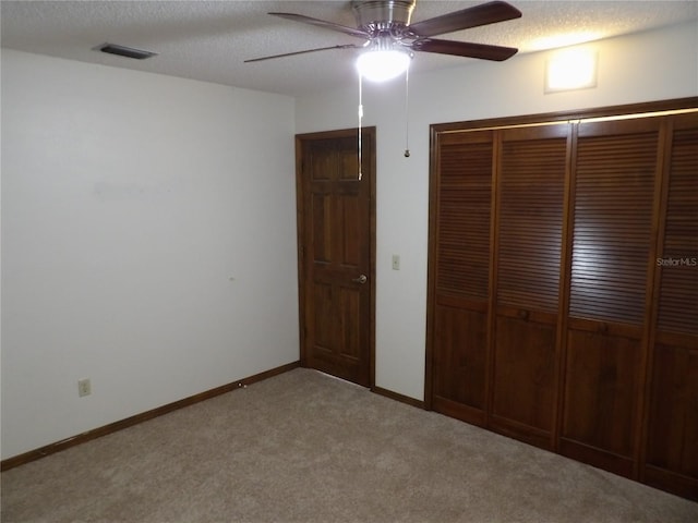 unfurnished bedroom with visible vents, a textured ceiling, a closet, carpet flooring, and baseboards