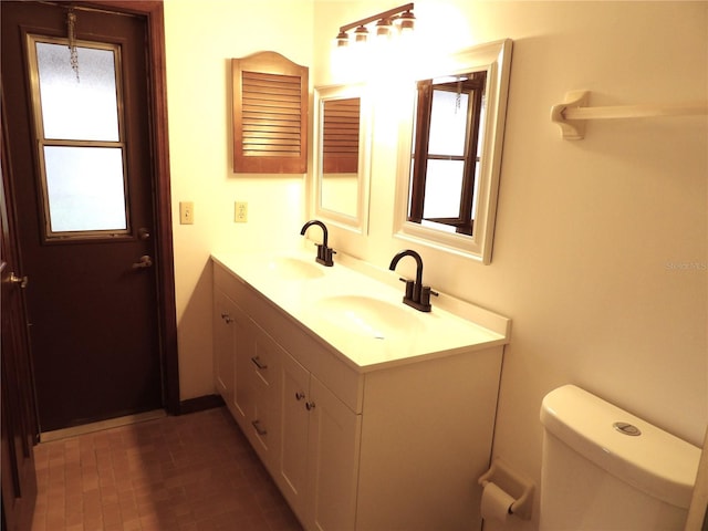 bathroom with a sink, toilet, and double vanity