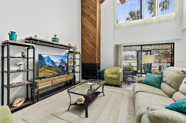 living room with hardwood / wood-style flooring, ceiling fan, and a towering ceiling