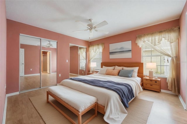 bedroom featuring ceiling fan, two closets, and light wood-type flooring