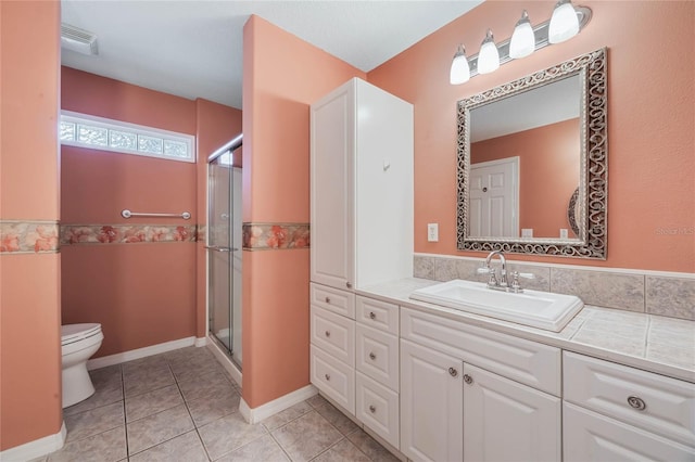 bathroom featuring tile patterned flooring, vanity, toilet, and an enclosed shower