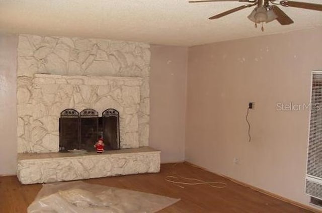 unfurnished living room with a fireplace, wood-type flooring, a textured ceiling, and ceiling fan