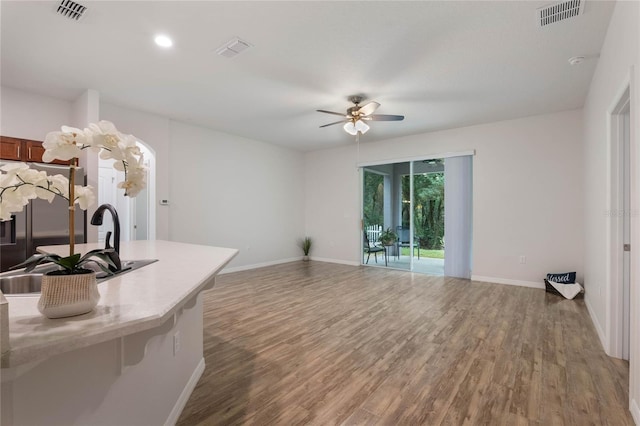 kitchen featuring a breakfast bar, hardwood / wood-style floors, ceiling fan, and sink