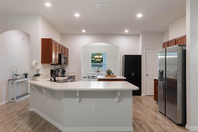 kitchen with an inviting chandelier, a kitchen breakfast bar, sink, light hardwood / wood-style floors, and stainless steel appliances