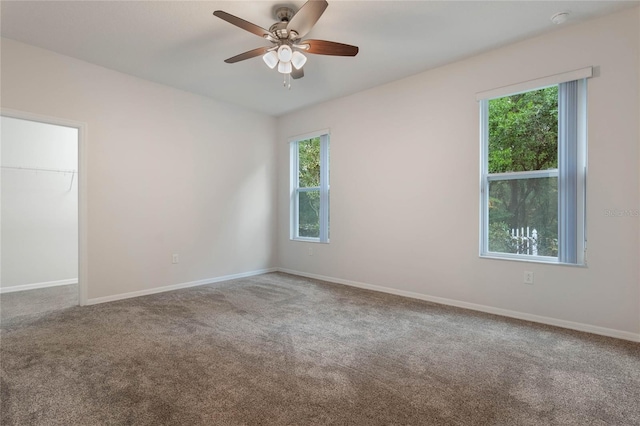 carpeted spare room featuring ceiling fan and a wealth of natural light