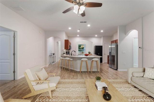 living room featuring ceiling fan, sink, and light hardwood / wood-style flooring