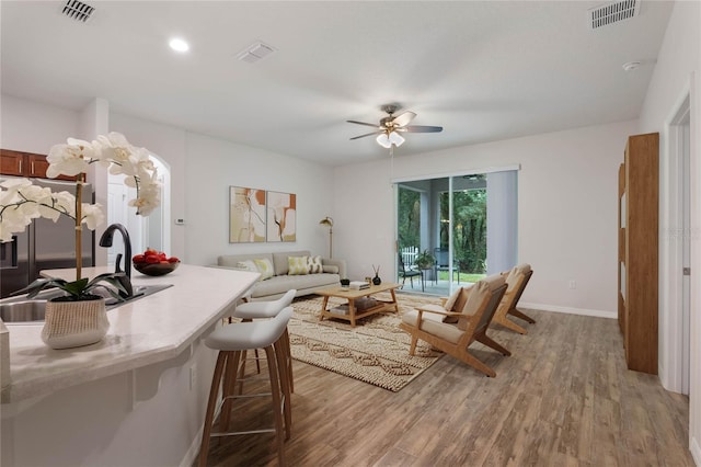 living area with visible vents, a ceiling fan, and wood finished floors