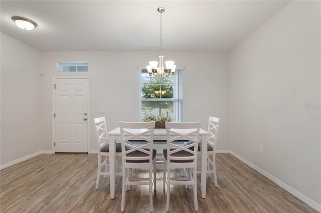 dining room with a chandelier, baseboards, and wood finished floors
