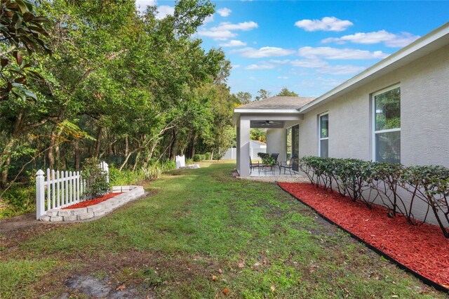 view of yard featuring a patio area, ceiling fan, and fence