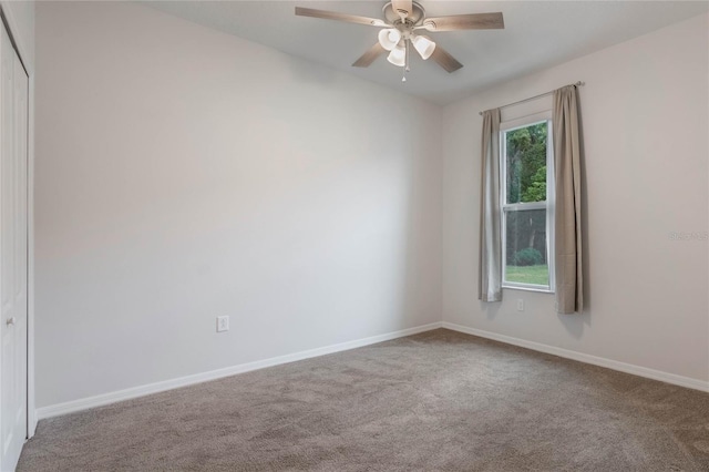 carpeted spare room featuring ceiling fan and baseboards