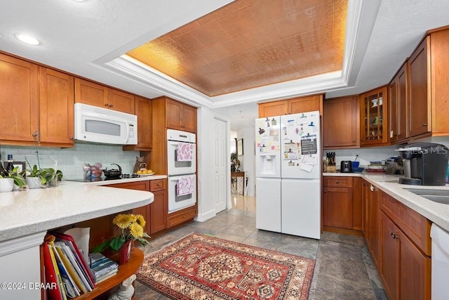 kitchen with white appliances, tasteful backsplash, a raised ceiling, and ornamental molding