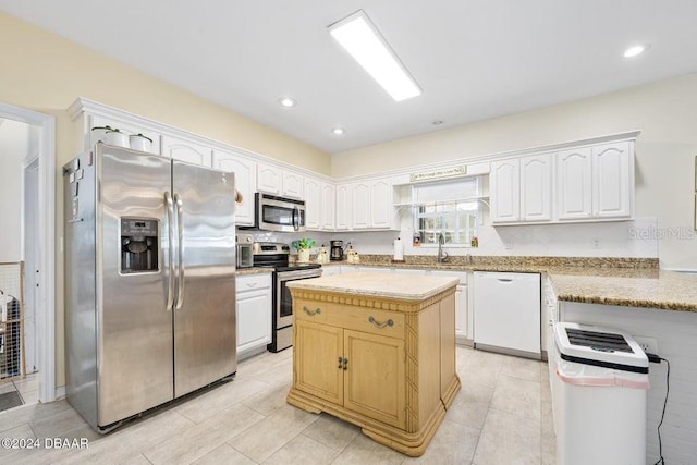 kitchen with stainless steel appliances, a kitchen island, sink, and white cabinets