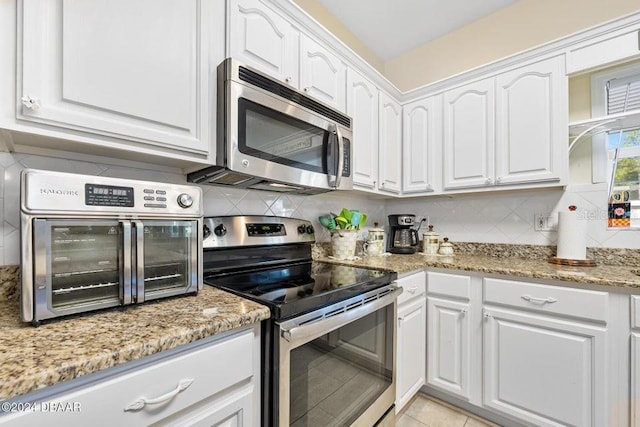 kitchen featuring backsplash, appliances with stainless steel finishes, light stone counters, and white cabinets